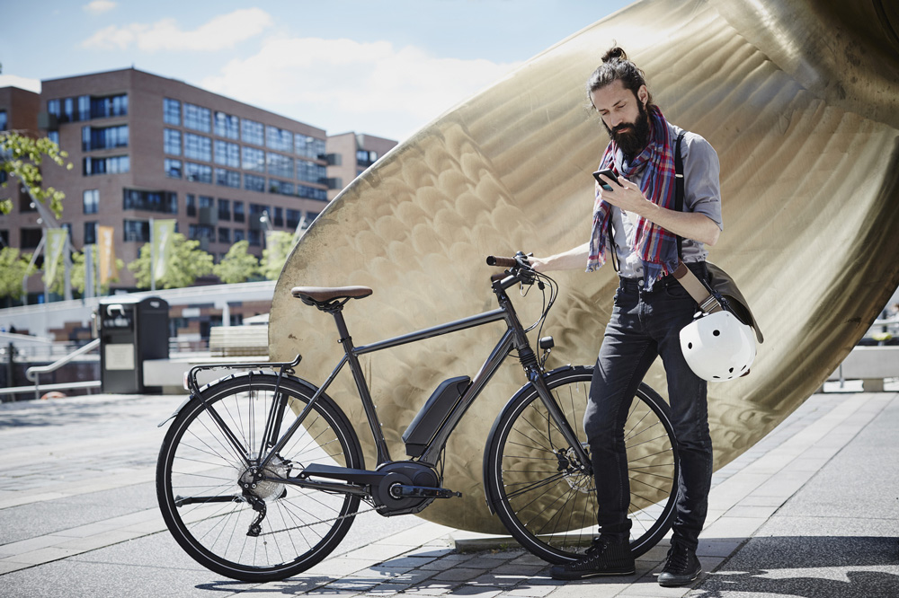 Mann steht mit Fahrrad in einer Smart City